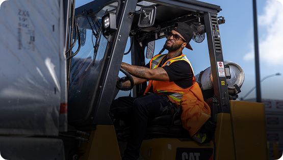 A man in an orange vest operating a forklift